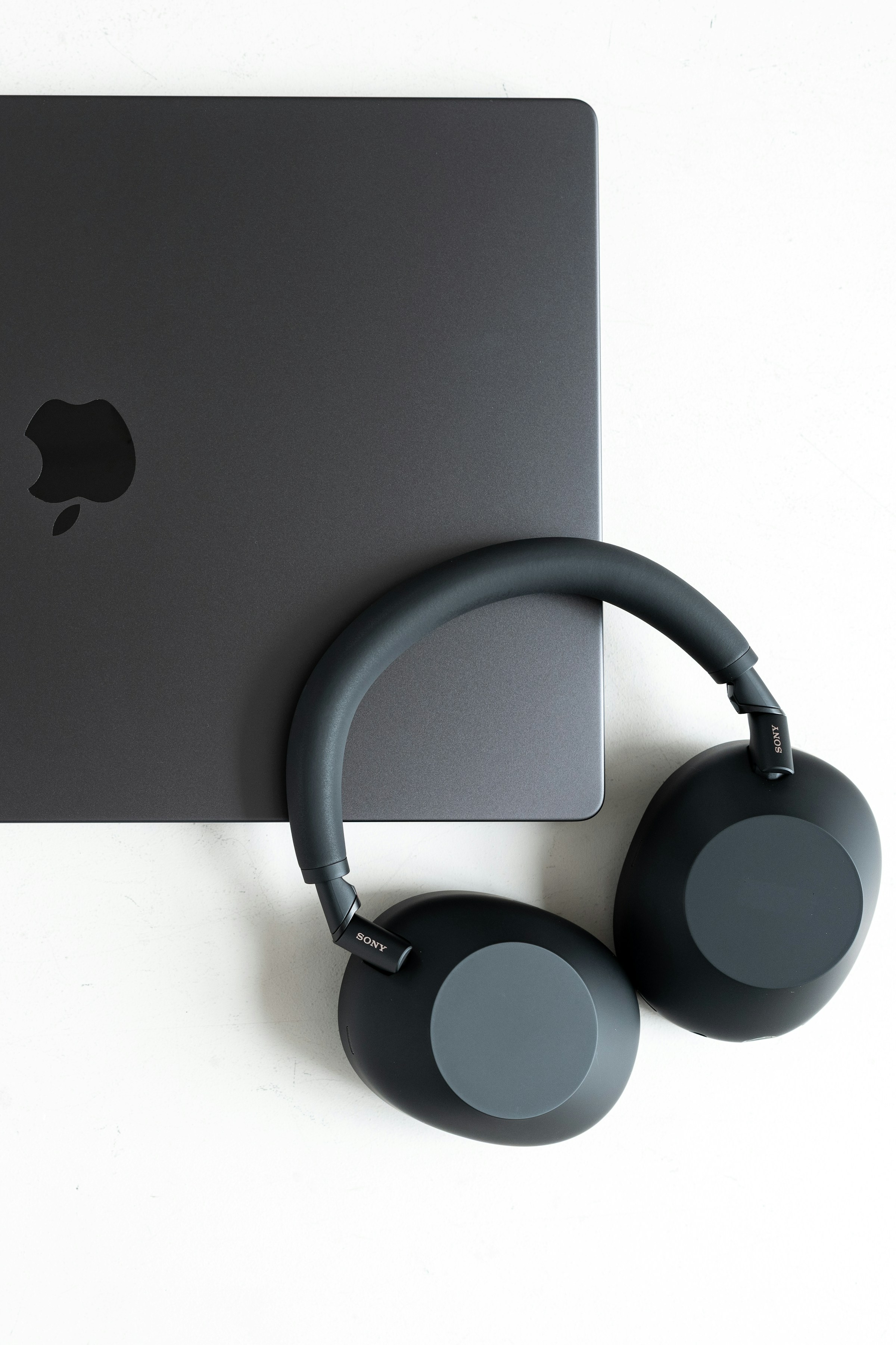 Černá sluchátka Sony WH-1000XM6 položená vedle zavřeného notebooku